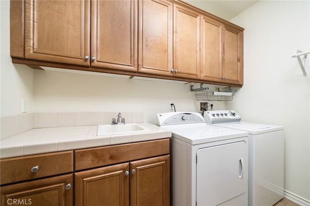 laundry room featuring washing machine and dryer, cabinet space, and a sink