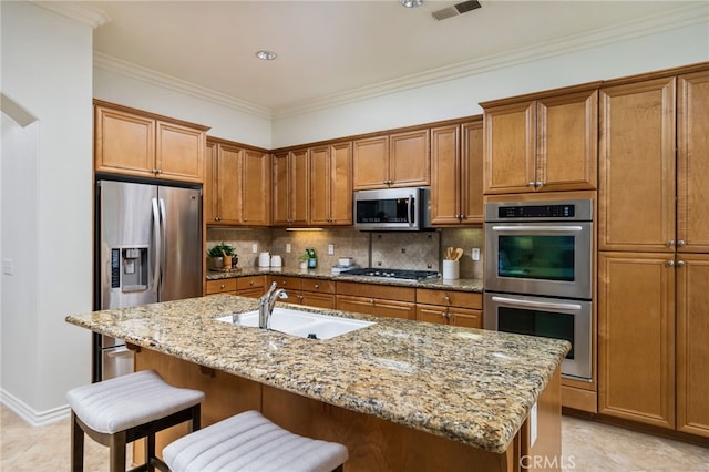 kitchen featuring a sink, visible vents, appliances with stainless steel finishes, brown cabinets, and tasteful backsplash