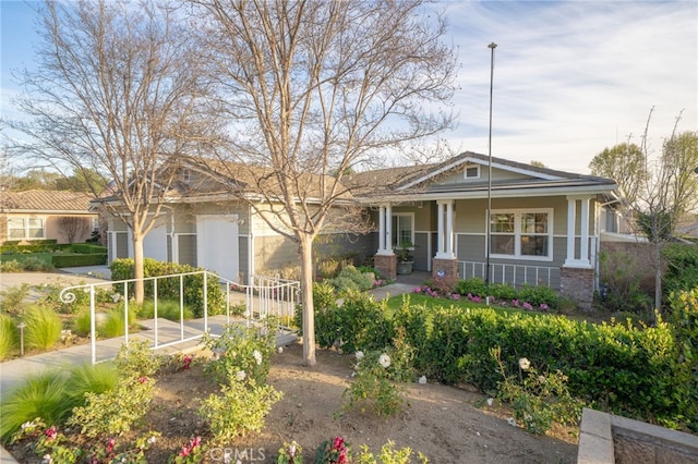 view of front of home with covered porch, brick siding, driveway, and an attached garage