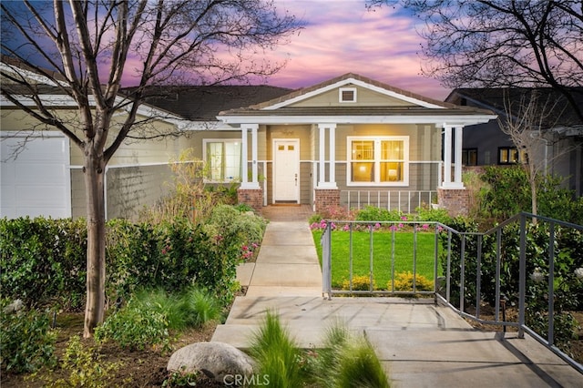 view of front of house featuring a fenced front yard, brick siding, a yard, covered porch, and a gate