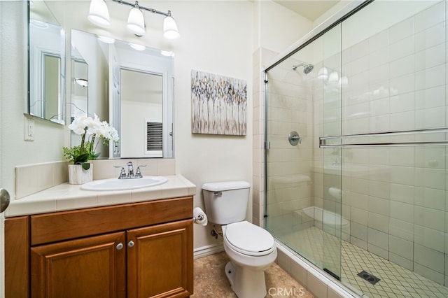 bathroom featuring vanity, a shower stall, toilet, and baseboards