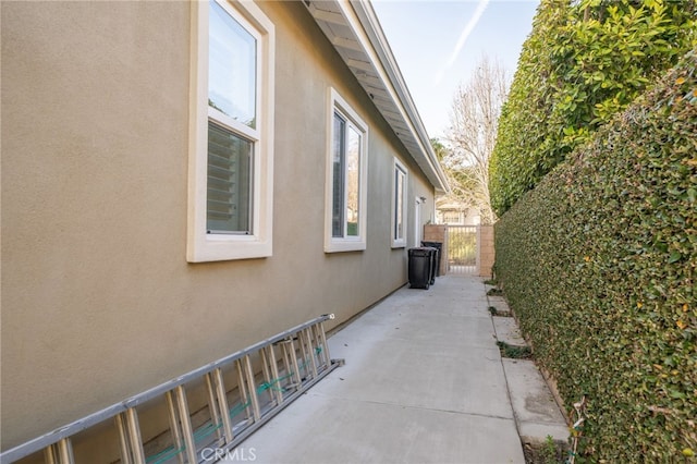 view of side of home featuring a patio, fence, and stucco siding