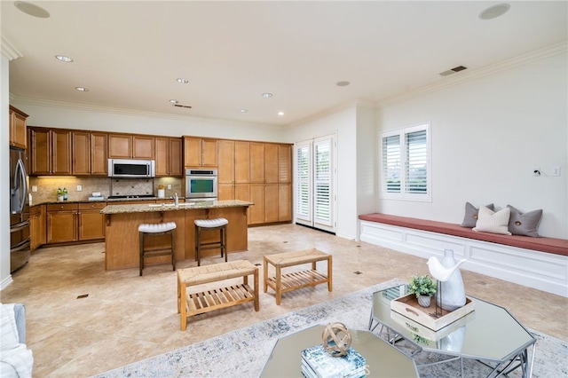 kitchen featuring tasteful backsplash, appliances with stainless steel finishes, a breakfast bar area, and ornamental molding