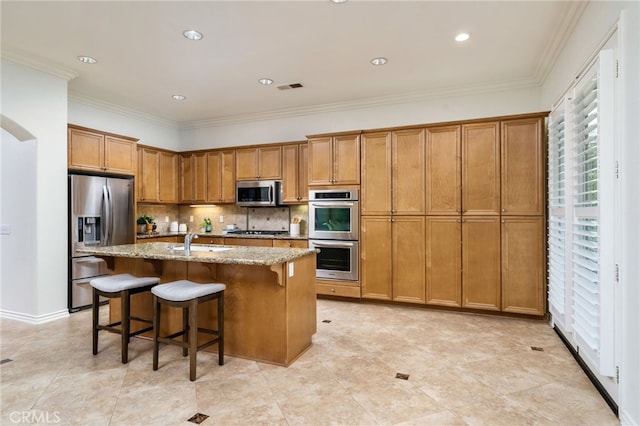 kitchen with tasteful backsplash, visible vents, brown cabinetry, appliances with stainless steel finishes, and light stone countertops