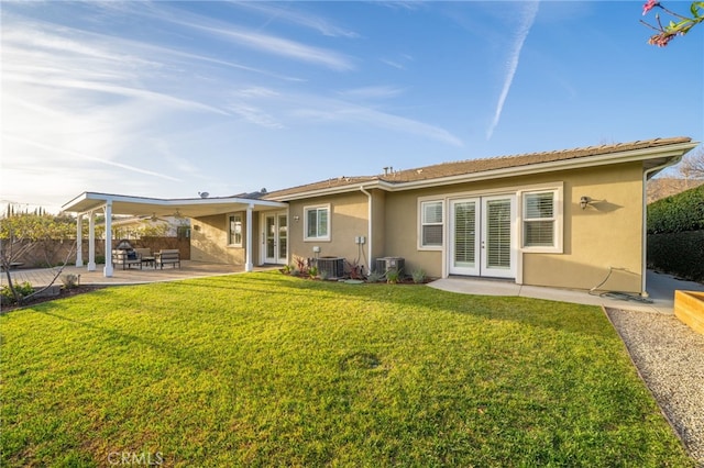 back of property with a yard, central AC, french doors, and stucco siding