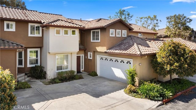 view of front of house featuring a garage, a tile roof, driveway, and stucco siding