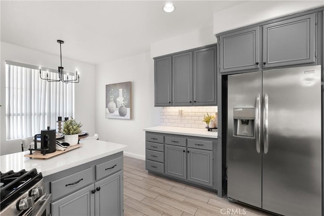 kitchen featuring stainless steel appliances, wood finish floors, gray cabinetry, and tasteful backsplash