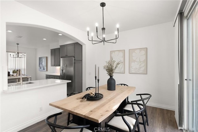 dining room with dark wood-type flooring, arched walkways, and a notable chandelier