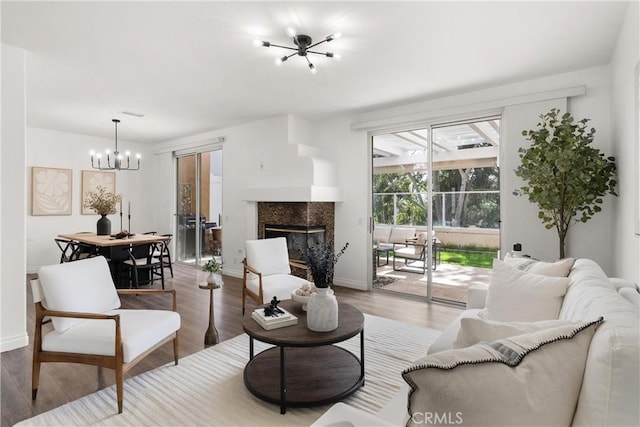 living area featuring a chandelier, wood finished floors, a high end fireplace, and baseboards