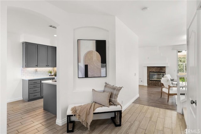 living area with baseboards, a premium fireplace, visible vents, and wood finish floors