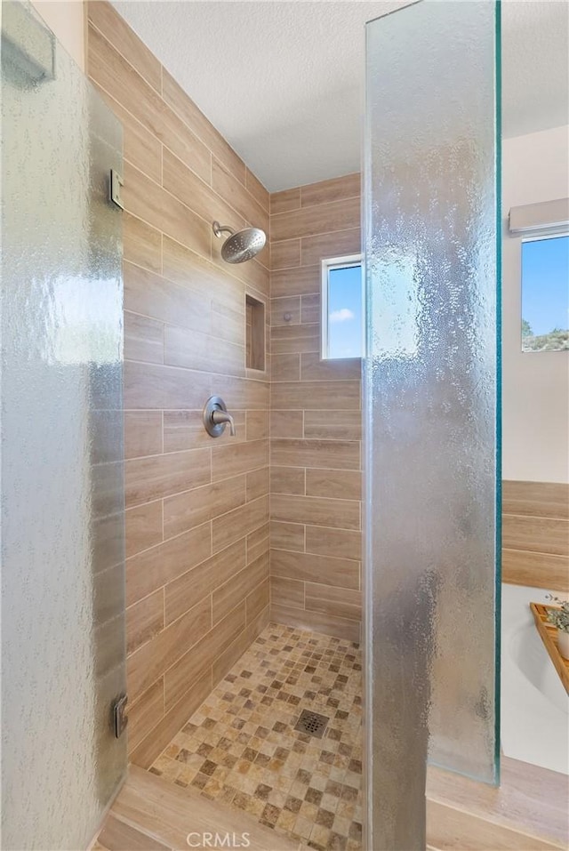 full bathroom with a textured ceiling and a stall shower