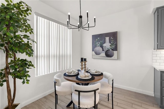 dining space featuring a notable chandelier, light wood finished floors, and baseboards