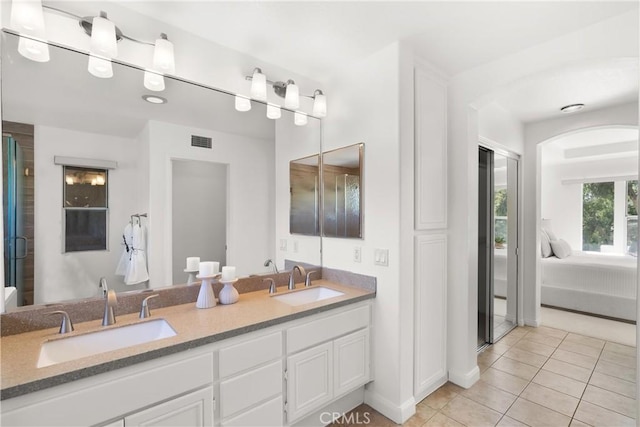 bathroom with tile patterned flooring, ensuite bath, visible vents, and a sink