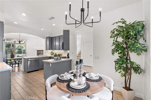 dining room with arched walkways, recessed lighting, light wood-style floors, baseboards, and an inviting chandelier