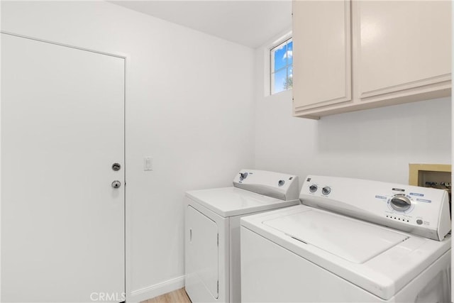 washroom featuring baseboards, cabinet space, and washer and dryer