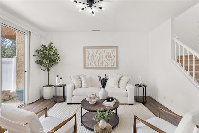 living room featuring stairs, wood finished floors, visible vents, and baseboards