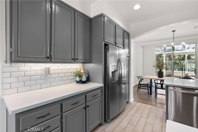 kitchen with stainless steel appliances, backsplash, light countertops, and gray cabinetry