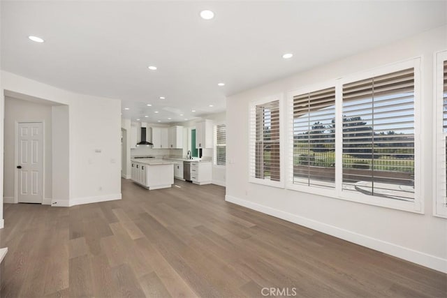 unfurnished living room featuring a sink, baseboards, wood finished floors, and recessed lighting