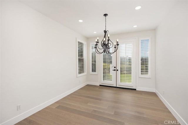 unfurnished dining area with baseboards, a chandelier, wood finished floors, and recessed lighting