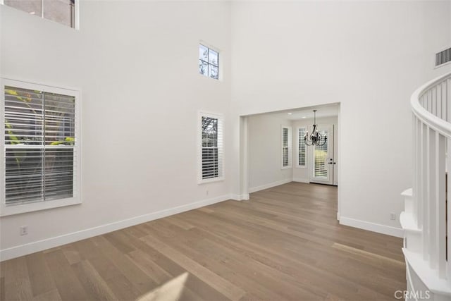 interior space featuring a chandelier, wood finished floors, a towering ceiling, and baseboards