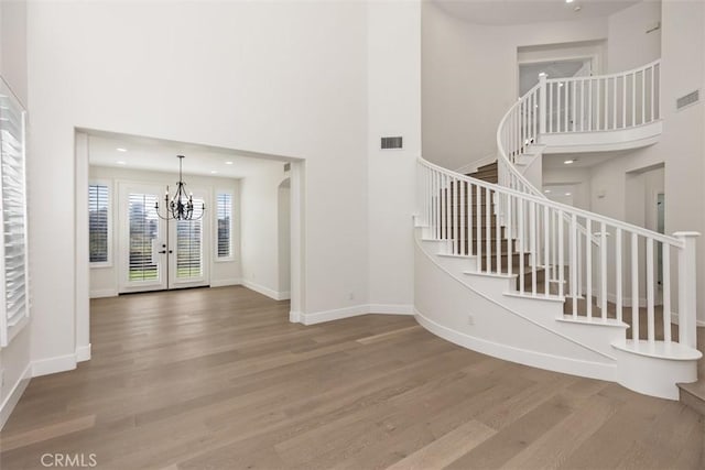 foyer entrance featuring a high ceiling, wood finished floors, visible vents, baseboards, and stairway