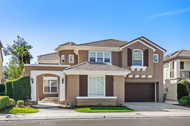 view of front of property featuring a garage, concrete driveway, a tiled roof, and stucco siding