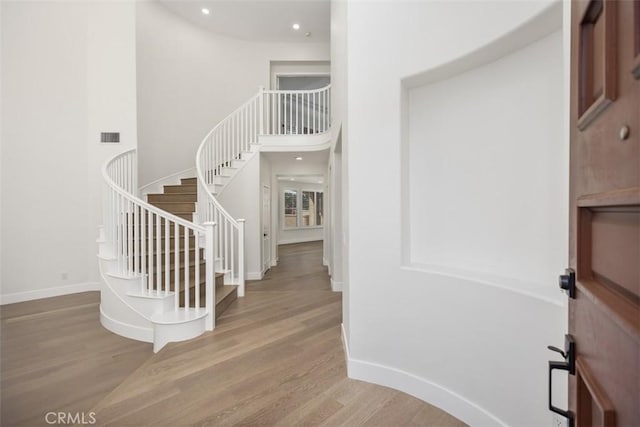 entryway featuring baseboards, stairs, visible vents, and wood finished floors