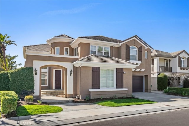 view of front of home featuring concrete driveway, a tile roof, an attached garage, and stucco siding