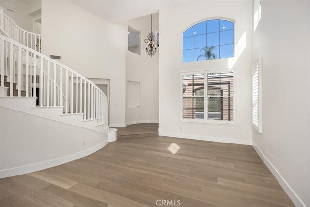 entryway with stairs, an inviting chandelier, wood finished floors, and baseboards