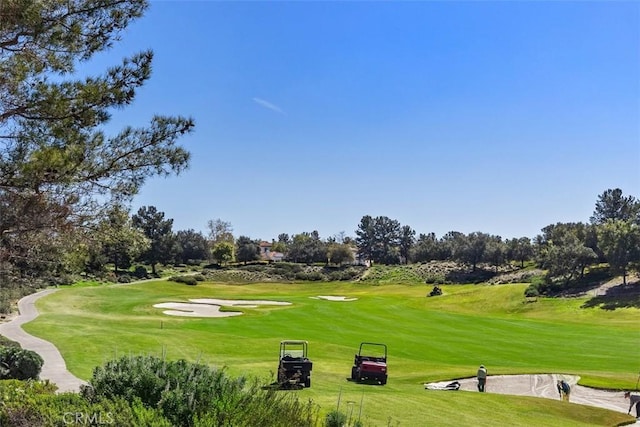 view of property's community featuring view of golf course and a yard