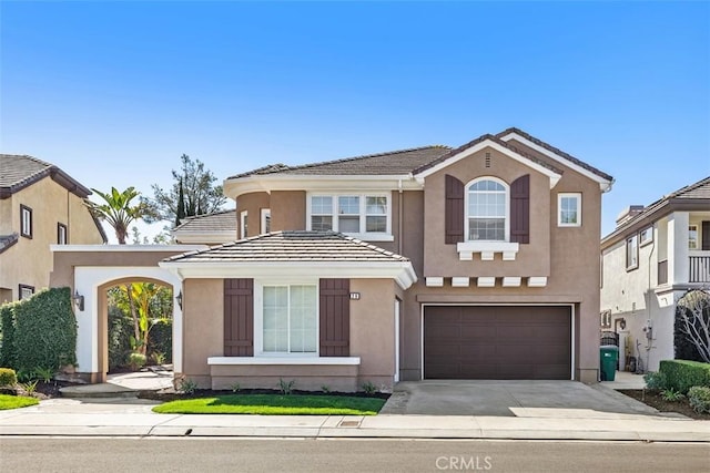 view of front of house with driveway, an attached garage, a tile roof, and stucco siding