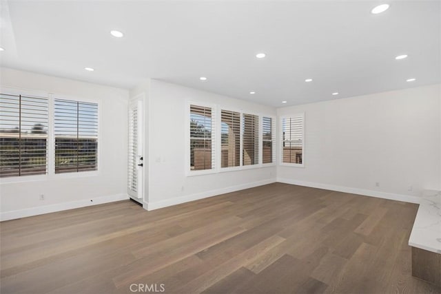 unfurnished room featuring baseboards, wood finished floors, and recessed lighting