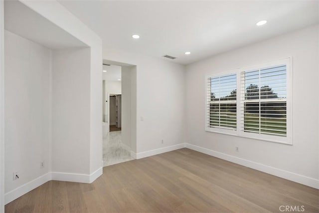 unfurnished room with recessed lighting, wood finished floors, visible vents, and baseboards