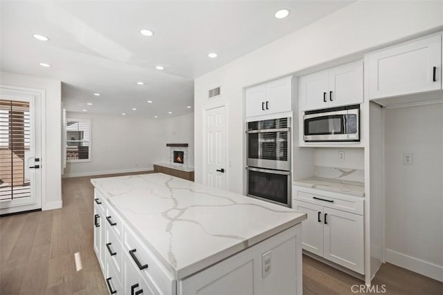 kitchen featuring visible vents, a kitchen island, appliances with stainless steel finishes, and white cabinets