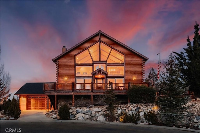 view of front of property featuring a deck, driveway, a chimney, and log siding