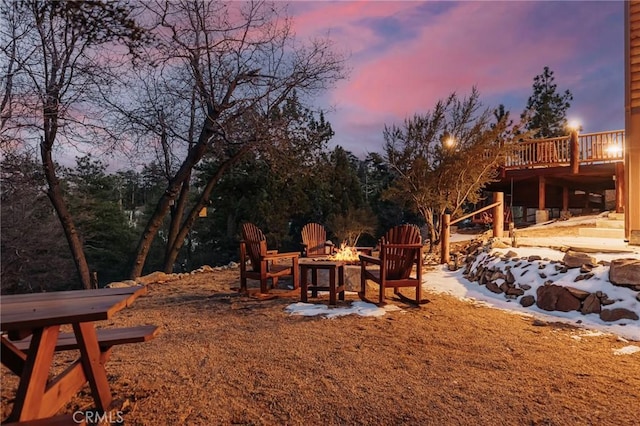 yard at dusk with an outdoor fire pit and a deck