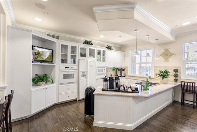 kitchen with visible vents, a peninsula, white appliances, white cabinetry, and dark wood-type flooring