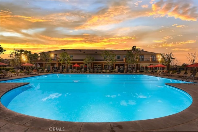 pool at dusk with a community pool and a patio area