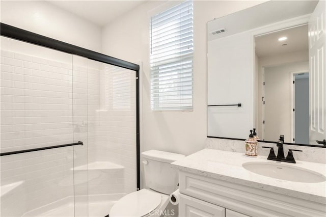 full bathroom featuring vanity, a stall shower, toilet, and visible vents