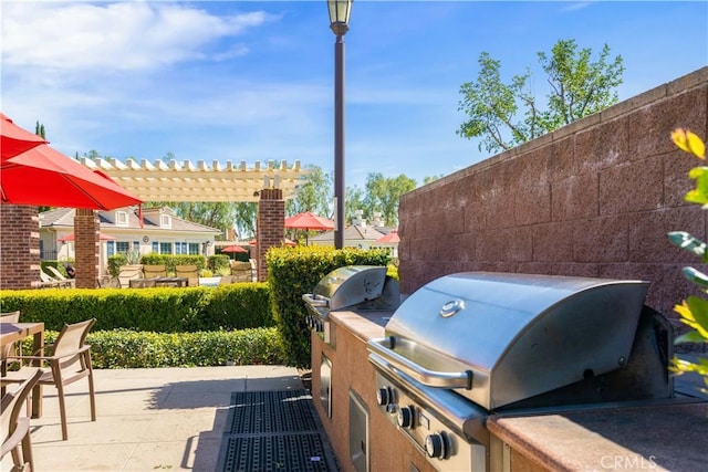 view of patio with exterior kitchen, a pergola, and a grill
