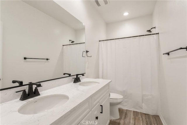 full bathroom featuring a sink, toilet, wood finished floors, and visible vents