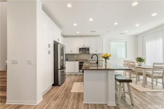 kitchen with a sink, white cabinets, stainless steel appliances, and light wood finished floors