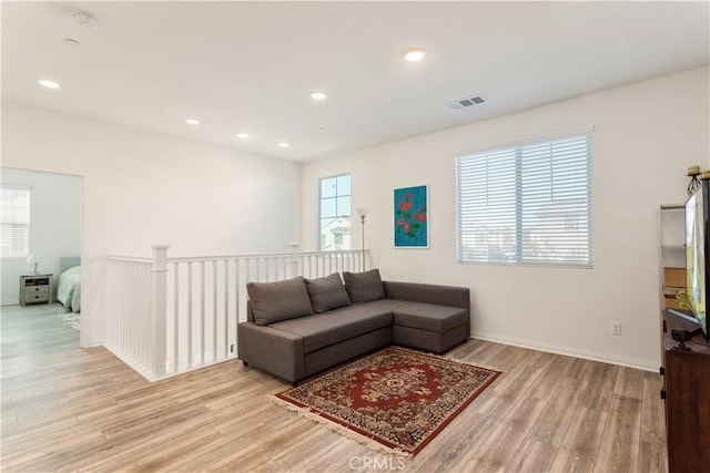 living area with baseboards, visible vents, plenty of natural light, and light wood-style flooring