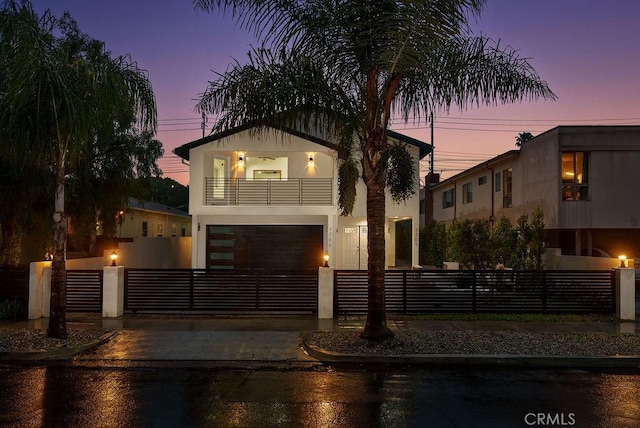 contemporary home featuring a fenced front yard, stucco siding, driveway, and a balcony