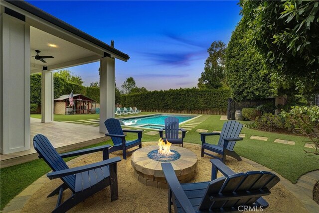 view of patio featuring an outdoor fire pit, a pool with connected hot tub, fence, and ceiling fan