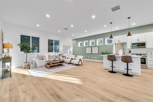 living area featuring light wood-style floors, recessed lighting, visible vents, and baseboards