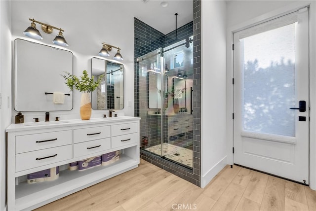 full bathroom with wood finished floors, a sink, and a healthy amount of sunlight