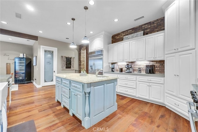 kitchen featuring white cabinets, stainless steel built in fridge, and visible vents