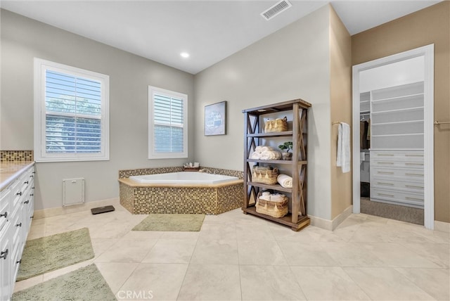 bathroom with a walk in closet, visible vents, tile patterned floors, and a bath