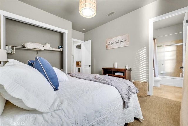 carpeted bedroom with visible vents and ensuite bath